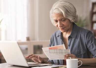 Woman looking at bills by laptop